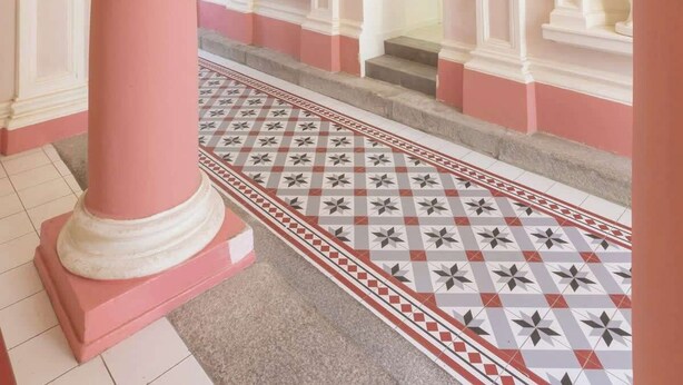 A grand hallway with pink columns, white moldings, and a patterned floor. - TurnKey | Angelo Roma Studio I (Praha 2)
