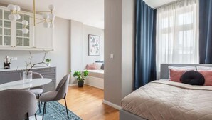A modern bedroom with a bed, a bedside table, a chair, a desk, and a window with curtains. - TurnKey | Angelo Roma Studio I (Praha 2)