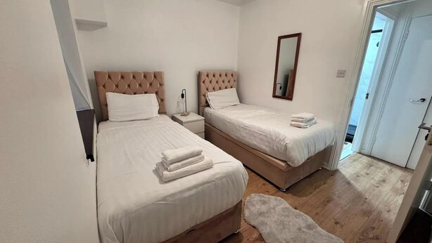 Una camera da letto con due letti, un comodino, uno specchio e un pavimento in legno.