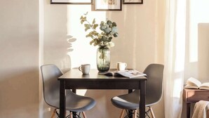 Un comedor con una mesa, sillas e impresiones enmarcadas de motivos botánicos en la pared.