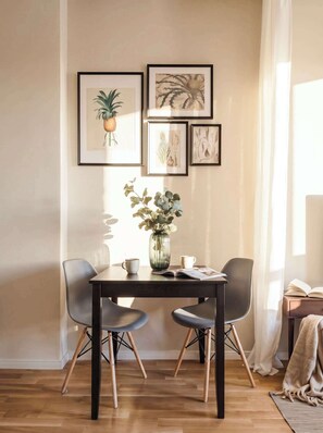 A dining area with a table, chairs, and framed botanical prints on the wall. - TurnKey | King George Studio with Balcony II (Praha 3)