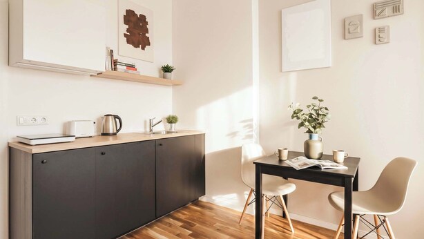 A modern kitchen with a wooden countertop, a sink, and a dining area with a table and chairs.