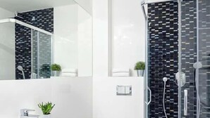 A modern bathroom with a white sink, toilet, and glass-enclosed shower.