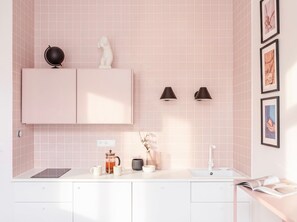 A modern kitchen with pink tiles, a white countertop, a coffee maker, and a sink. - TurnKey | Florenc Studio by Central Bus Station (Praha 8)