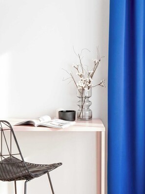 A minimalist desk setup with a chair, a vase with branches and berries, a book, and a candle holder. - TurnKey | Florenc Studio by Central Bus Station (Praha 8)