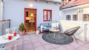 An outdoor patio with a sofa, a dining table, and a chair.