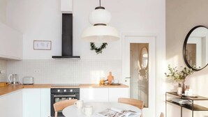 A modern kitchen with a central island, white cabinetry, and a round dining table with chairs.