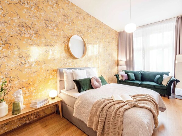 Une chambre à coucher avec un lit, une table de chevet, une lampe et un canapé vert.