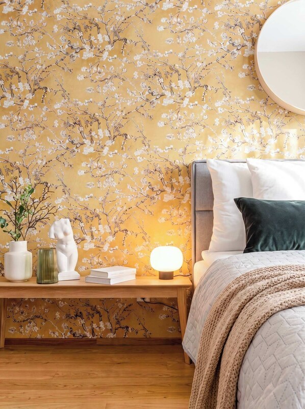 A bedroom with a bed, bedside table, lamp, and decorative items.