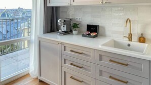 A modern kitchen with grey cabinets, a white countertop, and a large window offering a city view. - TurnKey | Angelo Roma Studio - Premium View (Praha 2)