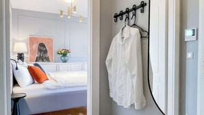 A bedroom with a bed, bedside table, lamp, and a wall-mounted mirror. - TurnKey | Angelo Roma Studio - Premium View (Praha 2)