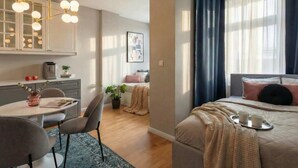 A modern hotel room with a dining area, a bed with a tray of cups, and a large window with curtains. - TurnKey | Angelo Roma Studio III (Praha 2)