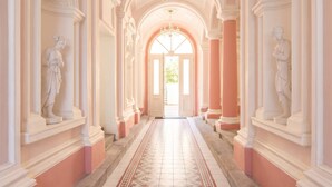 A grand hallway with classical architecture, including columns and statues, leading to a bright doorway. - TurnKey | Angelo Roma Studio III (Praha 2)