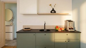A modern kitchen with a dark countertop, a sink, a coffee machine, and a vase with flowers. - TurnKey | Angelo Roma Studio VI (Praha 2)