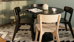 A modern kitchen with a round dining table, black chairs, a white vase with dried flowers, and a coffee machine. - TurnKey | Angelo Roma Studio VI (Praha 2)