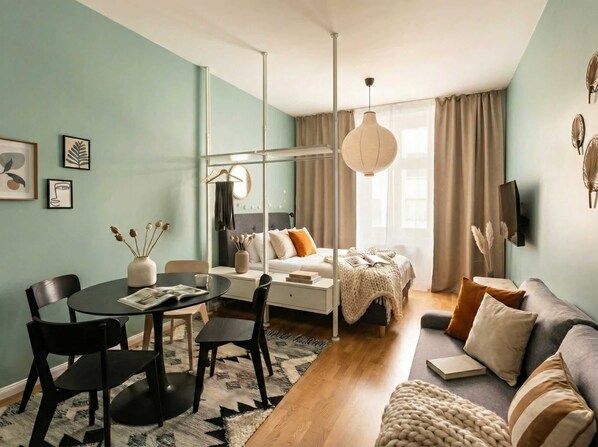 A modern living room with a sofa, a dining table with chairs, a coffee table, and a TV mounted on the wall.