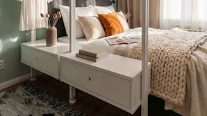 A bedroom with a bed, bedside tables, a hanging lamp, a mirror, and a window with curtains. - TurnKey | Angelo Roma Studio VI (Praha 2)