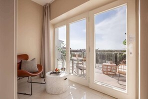 A modern living room with a large sliding glass door leading to an outdoor balcony with wicker furniture.