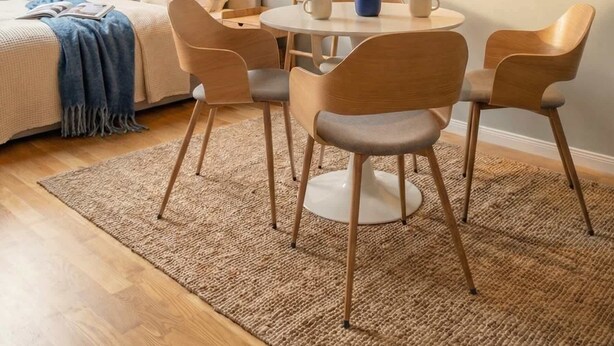 A cozy room with a bed, a round table with chairs, a ladder, and a framed artwork on the wall.