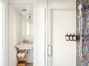 A modern bathroom with a glass shower enclosure, a white sink, and a mirror.
