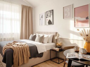 A modern bedroom with a bed, bedside table, and a reading area with a chair and table.