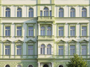 A multi-story building with a symmetrical facade, featuring evenly spaced windows, decorative moldings, and a central entrance with a balcony.