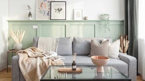 A living room with a sofa, a glass coffee table, and a side table with a vase.