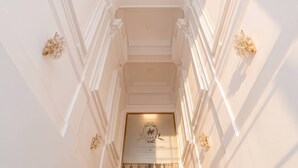 A grand staircase with ornate wall moldings and a chandelier at the top.