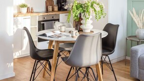 A modern kitchen with white cabinets, a dining table with chairs, and a coffee machine.