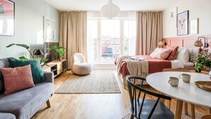 Un salon moderne avec un canapé, une table à manger et un lit recouvert d’une couverture rouge.