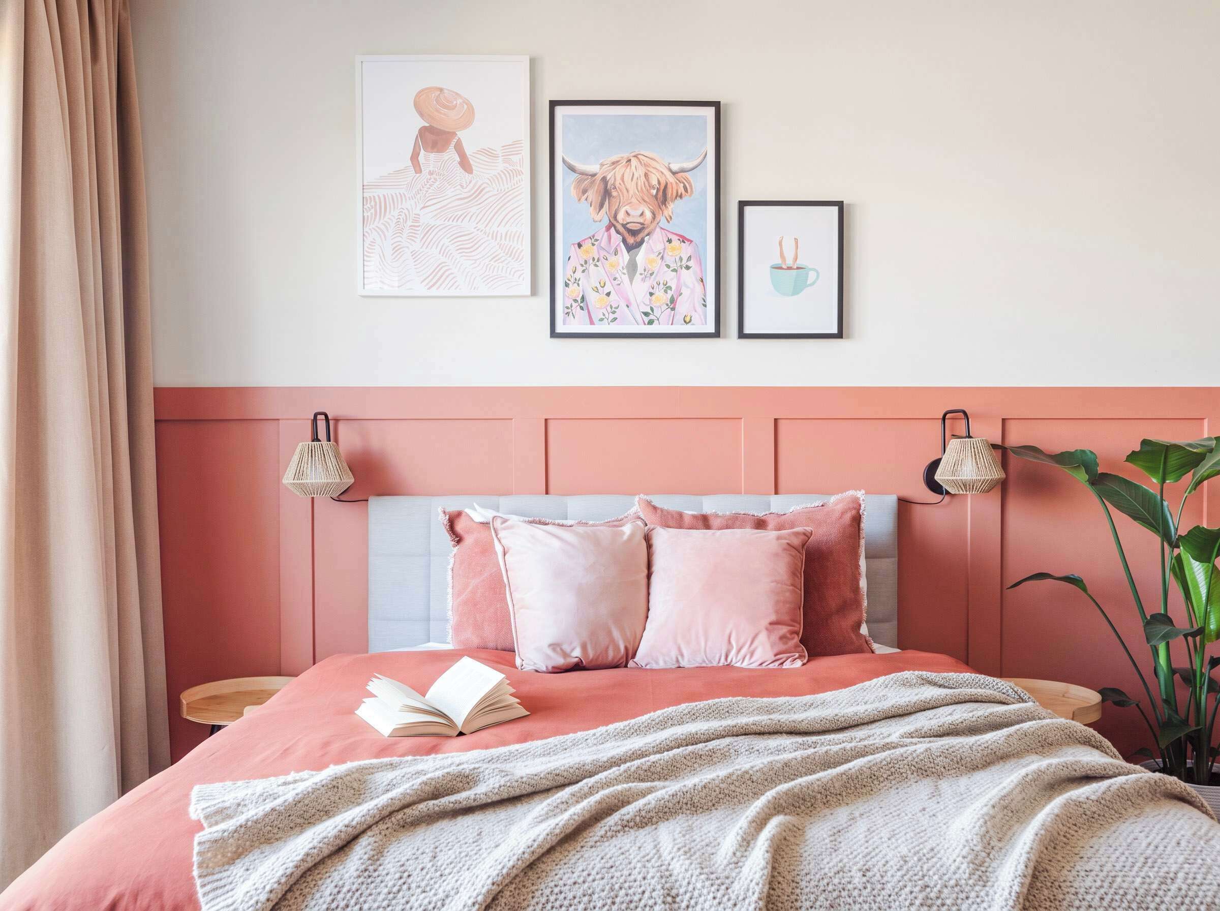 A bedroom with a bed, pillows, a blanket, and wall art.