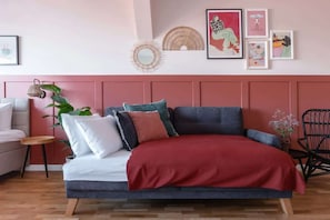 Una sala de estar moderna con un sofá, una mesa de centro y una silla. Hay decoraciones en la pared y una planta.