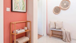 A hallway with a wooden shelf, a framed artwork, and a bench with cushions. - TurnKey | Letna Park Apartment II –Premium Terrace (Praha 7)