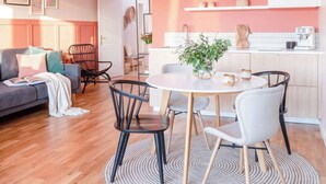 A modern living room with a sofa, a dining table with chairs, a kitchen area with a sink and cabinets, and a hallway with a door. - TurnKey | Letna Park Apartment II –Premium Terrace (Praha 7)