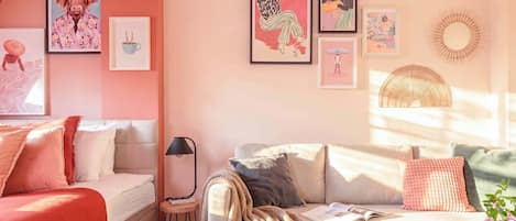 Una sala de estar acogedora con un sofá, una mesita y una lámpara. Hay obras de arte enmarcadas en la pared.