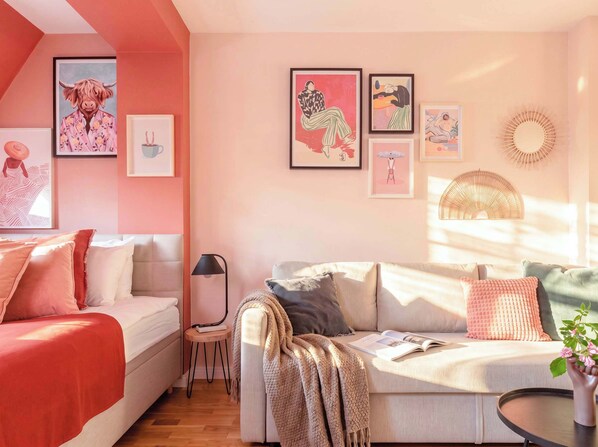 Una sala de estar acogedora con un sofá, una mesita y una lámpara. Hay obras de arte enmarcadas en la pared.