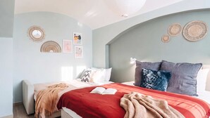 A bedroom with a bed, a bedside table, a lamp, and wall decorations.