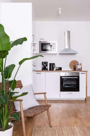 Una cocina moderna con armarios blancos, microondas, cafetera y horno.