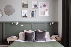 Un dormitorio moderno con cabecera verde, cama con ropa de cama blanca y gris, y una obra de arte en la pared.