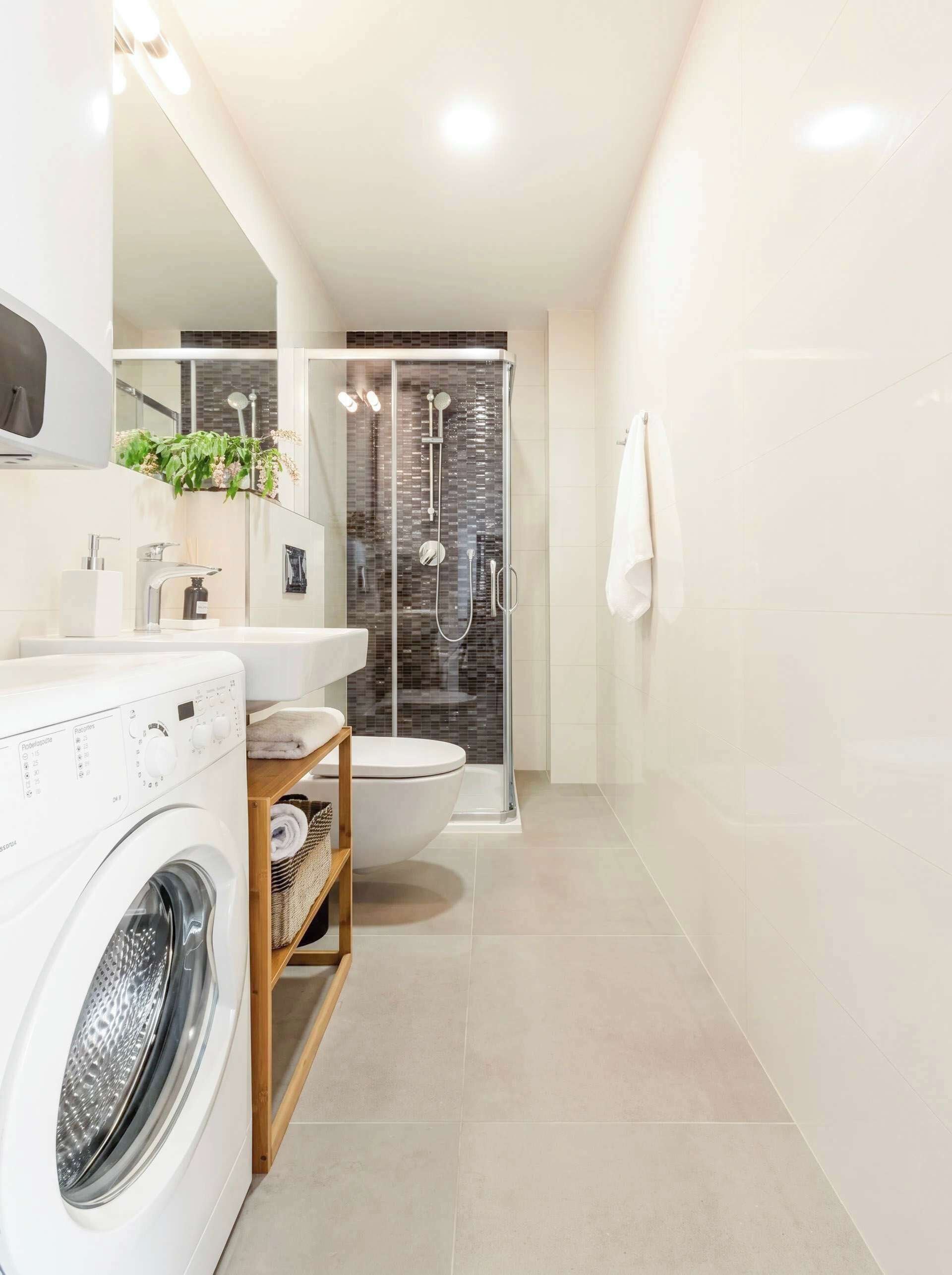 Ein modernes Badezimmer mit Waschmaschine, Toilette und Duschbereich.