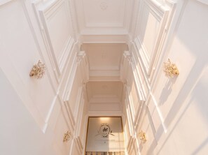 A grand staircase with ornate wall moldings and a chandelier at the top. - TurnKey | National Museum Apartment V (Praha 1)