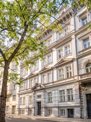 A multi-story building with classical architecture, featuring a central entrance with a decorative archway and multiple windows. - TurnKey | National Museum Apartment V (Praha 1)