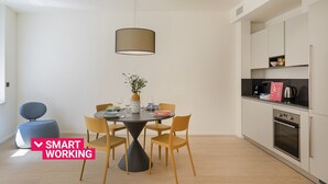 Eine moderne Küche mit weißen Schränken, einem eingebauten Ofen und einem Essbereich mit einem runden Tisch und Stühlen.