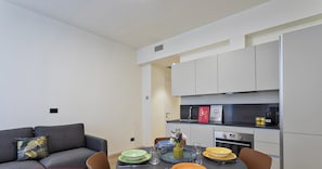 Ein modernes Apartment mit Essbereich, Küchenzeile und einem grauen Sofa.