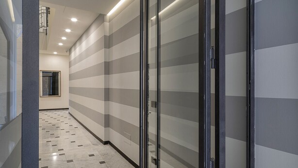 A hallway with striped walls and a tiled floor, leading to a door with a metal handle. - Riviera Flavour Apartments by Wonderful Italy - Verbena (Santa Margherita Ligure)