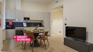 A compact kitchen with modern appliances, a dining area with a table and chairs, and a flat-screen TV. - Riviera Flavour Apartments by Wonderful Italy - Verbena (Santa Margherita Ligure)