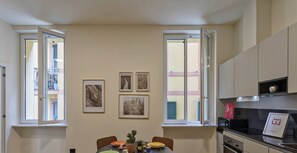 Una cocina moderna con comedor, con una mesa dispuesta para cuatro personas, un refrigerador y un microondas.