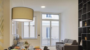 A modern dining area with a round table set for six, a sofa, and a bookshelf.