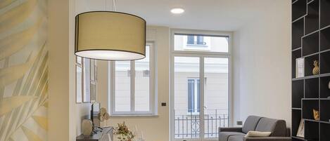 A modern dining area with a round table set for six, a sofa, and a bookshelf.