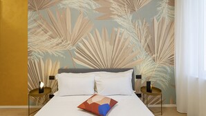 A bedroom with a bed, two bedside tables, and a wall with a leaf pattern.